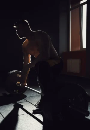 european caucasian athletic man waiting and preparing before lifting heavy barbell. silhouette of bodybuilder, posing in gym. deadlift with barbell. bent over the barbell. black and white