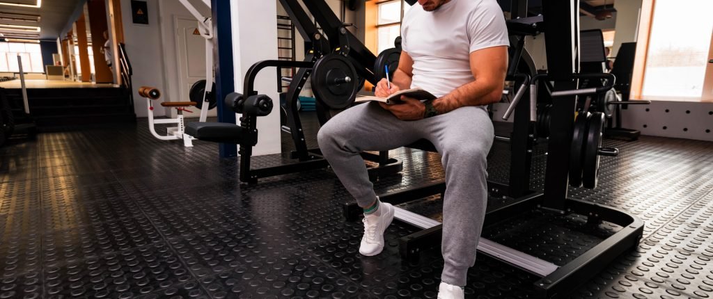 Fitness trainer writing workout program close up in gym. Sport, fitness and healthy life style concept.